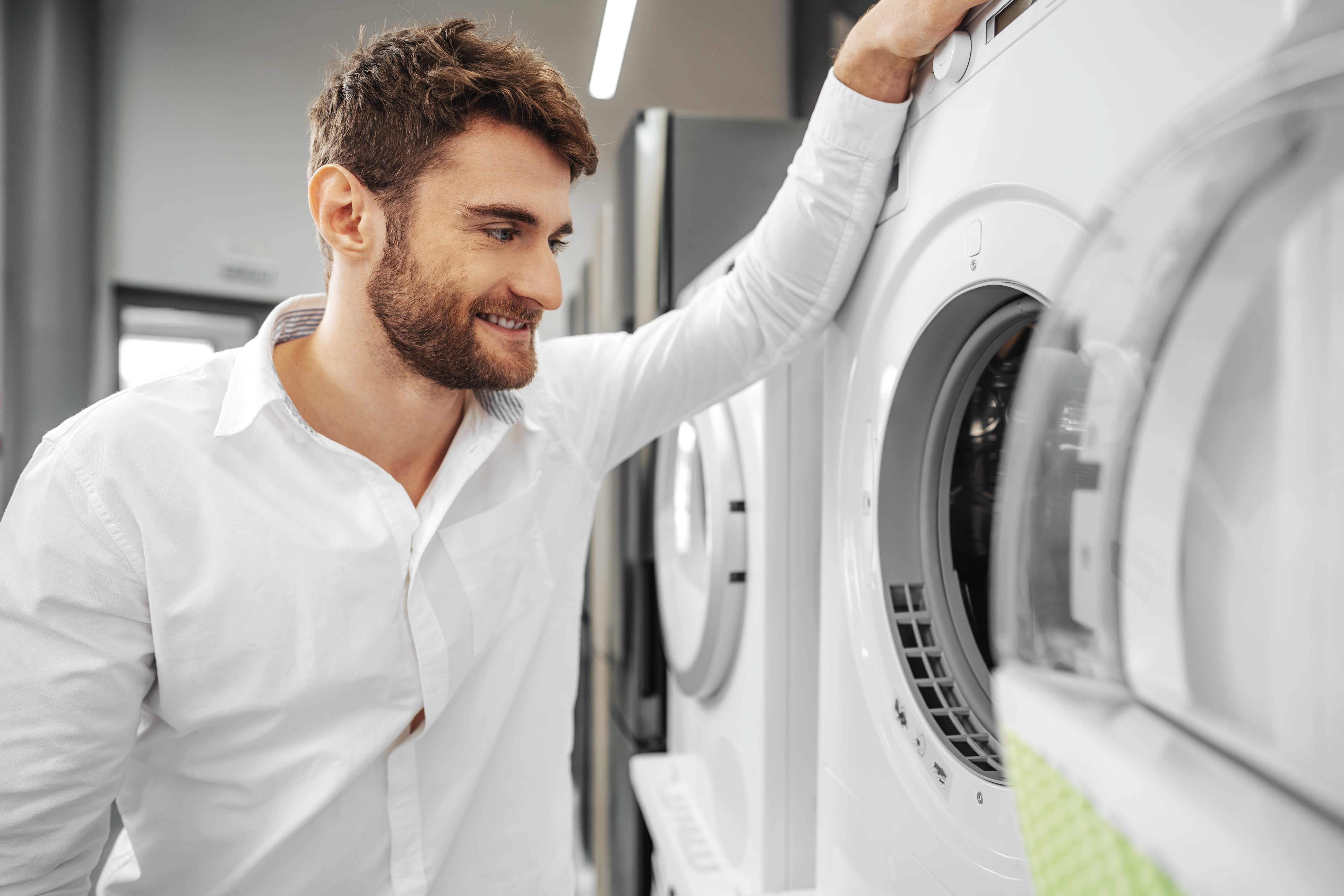 Young man choosing new washing machine